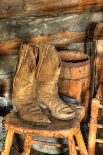 Old cowboy boots on a wooden chair with a barrel