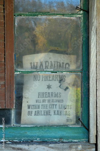 Old no firearms warning sign in old dirty window photo