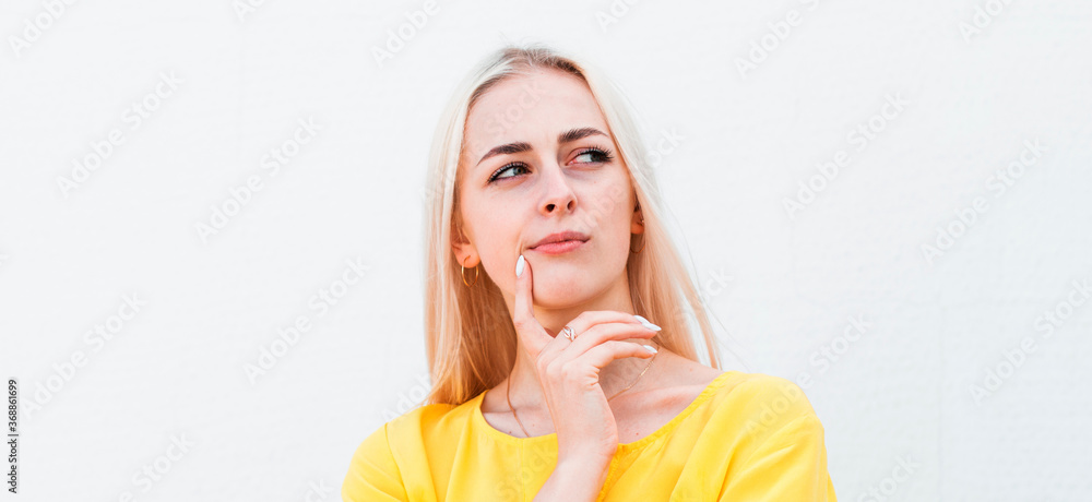 Close up portrait of pretty confident thoughtful woman, holding hand near the face, looking seriously up, standing over white background with copy space Close up portrait of pretty confident thoughtful woman, holding hand near the face, looking seriously up, standing over white background with copy space
