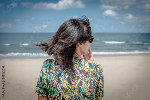 Mujer hispana de mediana edad junto al mar, pensativa mira el horizonte, asturias españa. photo