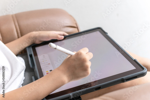 Little boy Drawing Digital Picture On Electronic Touch Tablet With Stylus Pen.