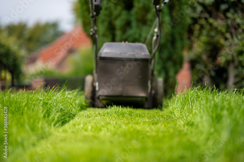 A lawn mower is standing in a freshly cut meadow.