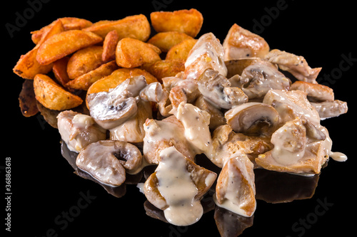 Delicious Chicken pieces with melted cheese and fried potatoes with reflection, isolated on black background