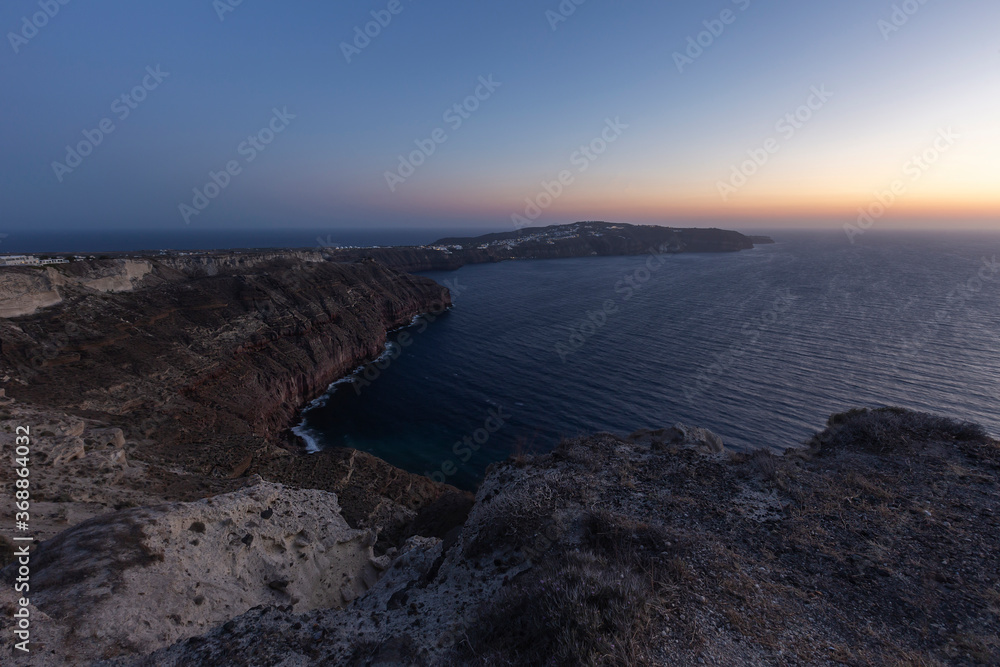Santorini sunset over the Caldera, on the right the coast of the island and on the left the sea and the setting sun.