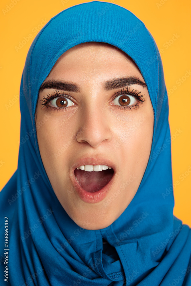 Shocked. Close up young muslim woman isolated on yellow studio background. Stylish, trendy. Human emotions, facial expression, sales, ad, shopping concept. Beautiful woman with well-kept skin. Shocked. Close up young muslim woman isolated on yellow studio background. Stylish, trendy. Human emotions, facial expression, sales, ad, shopping concept. Beautiful woman with well-kept skin.