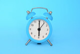 Blue alarm clock on blue background close up. 6 a.m., 6 p.m. Time concept.