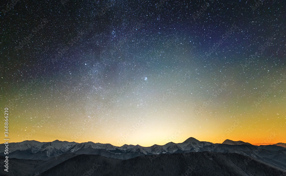 Amazing night mountain landscape with high peaks and bright starry sky above.