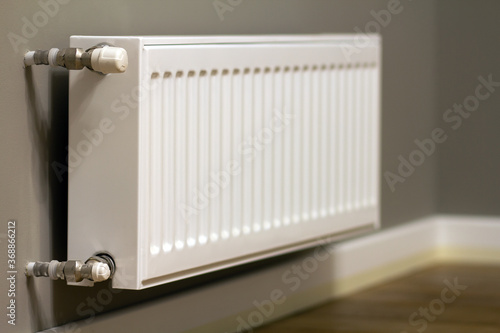 White metal heating radiator mounted on gray wall inside a room.