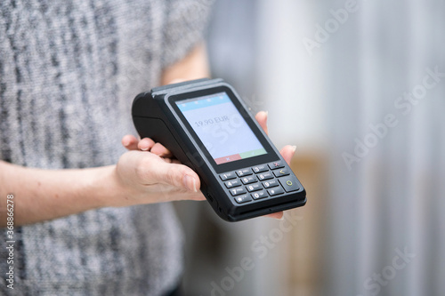 Detail of woman selling with credit card reader using a hygienic and wireless payment terminal.