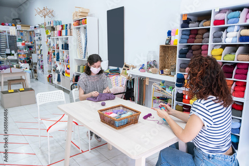 Group of women having fun and learning a hobby. Knitting lessons for young people with social distance during pandemic disease.