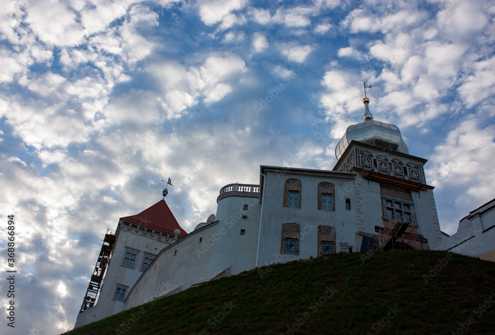 Sights and views of Grodno. Belarus. View of restored old castle on a high hill and a beautiful evening sky with white clouds..