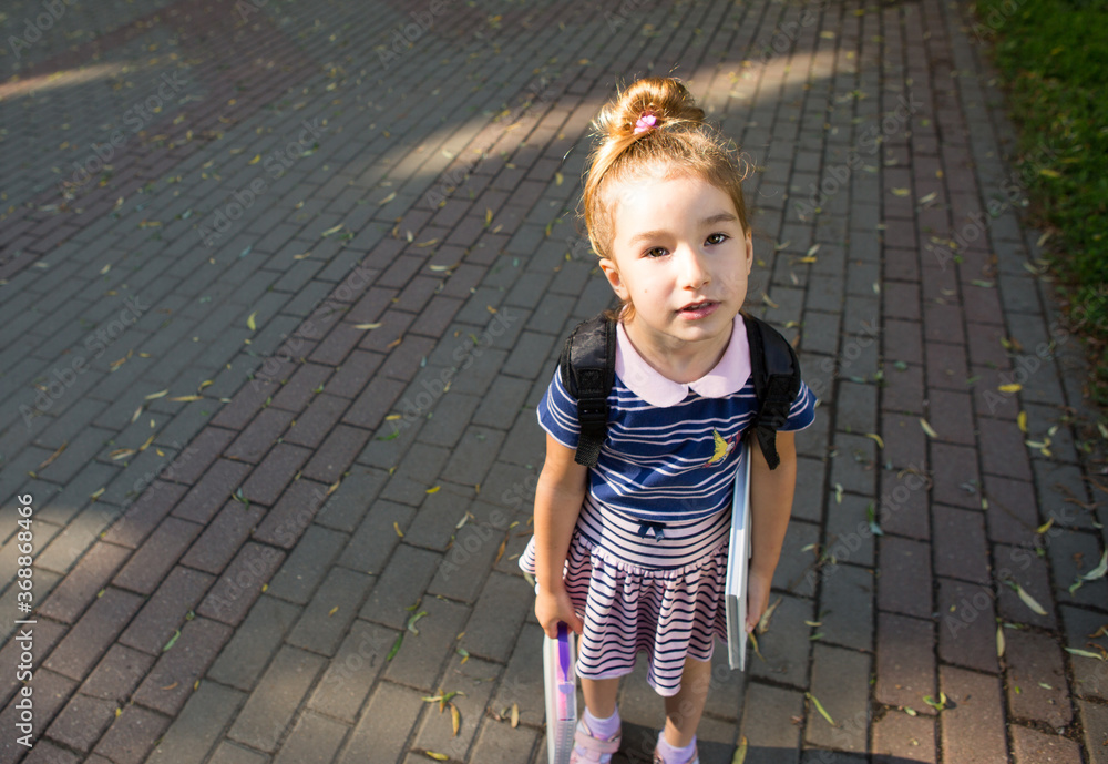 A tired elementary school girl looks sadly at the camera. Primary and pre-school education, learning difficulties, fatigue, return to school. Space for text. A tired elementary school girl looks sadly at the camera. Primary and pre-school education, learning difficulties, fatigue, return to school. Space for text.