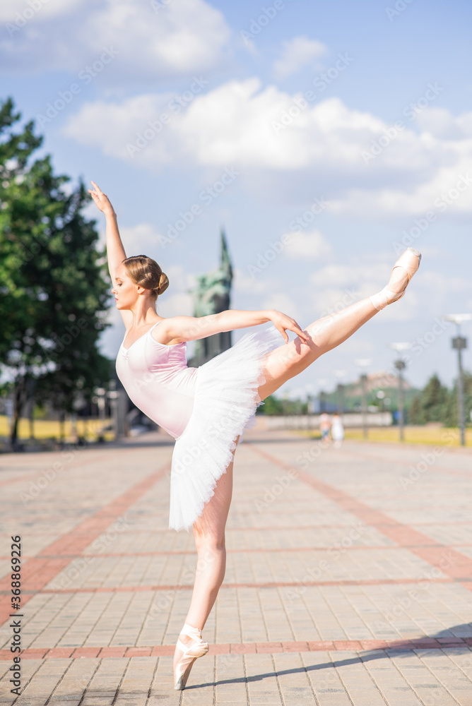 Young and beautiful ballerina posing on the street