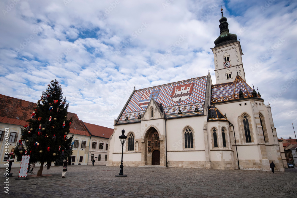 Fototapeta premium side view of the colorful St. Mark church at a cloudy day with a christmas tree at Zagreb, Croatia