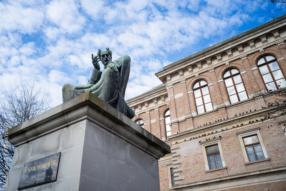 Obraz premium Zagreb / Croatia - December 31 / 2019 : the large statue of bishop strossmayer behind of the academy at a cloudy day