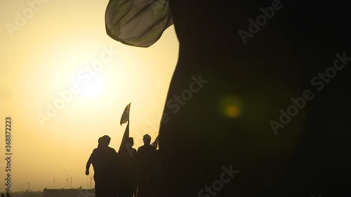 KARBALA, IRAQ - NOV 2017: Silhouette of crowd of pilgrims walking in Arbaeen pilgrimage at sunrise. Every year, millions of Shiite muslims come from all over the world to Karbala to walk Arbaeen photo