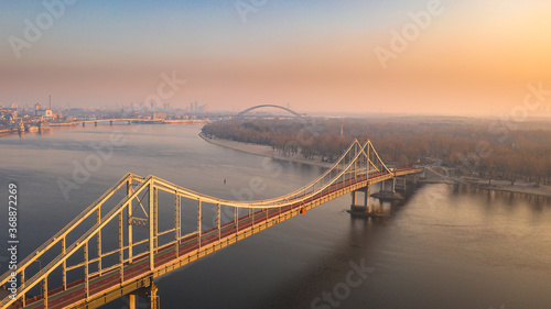 Aerial view of pedestrian Park bridge over the Dnipro river in Kyiv city on summer morning. Urban cityscape background at sunrise. Kiev, Ukraine
