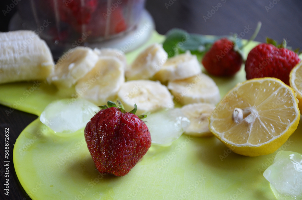 Strawberry and banana smoothie in the jar. Ingredients for making smoothies strawberry banana, frozen berries in a blender on a dark black wooden background.