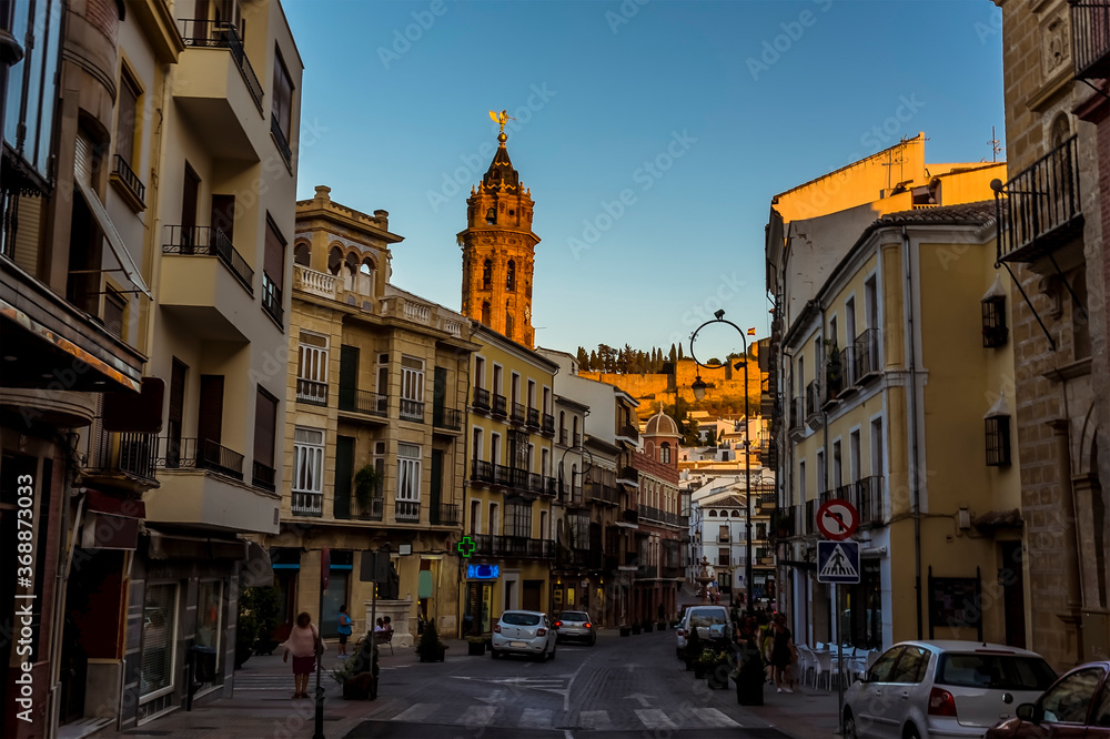 Naklejka premium A view down the main street of Antequera, Spain towards the Moorish Alcazaba palace fortress on a summers evening