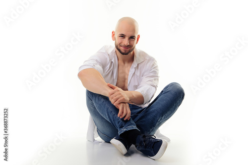 Foto relaxed guy smiling in camera and sit on floor isolated in white studio with cop