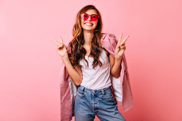 Beautiful white girl with long wavy hair posing with excitement. Indoor photo of optimistic ginger woman fooling around on pink background.