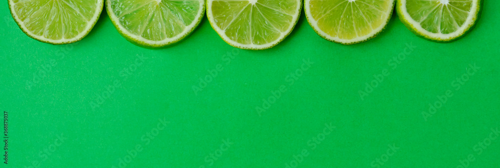 Halves of sliced limes on a green background. - obrazy, fototapety, plakaty 