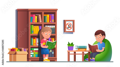 Kids reading books in library sitting on bag chair