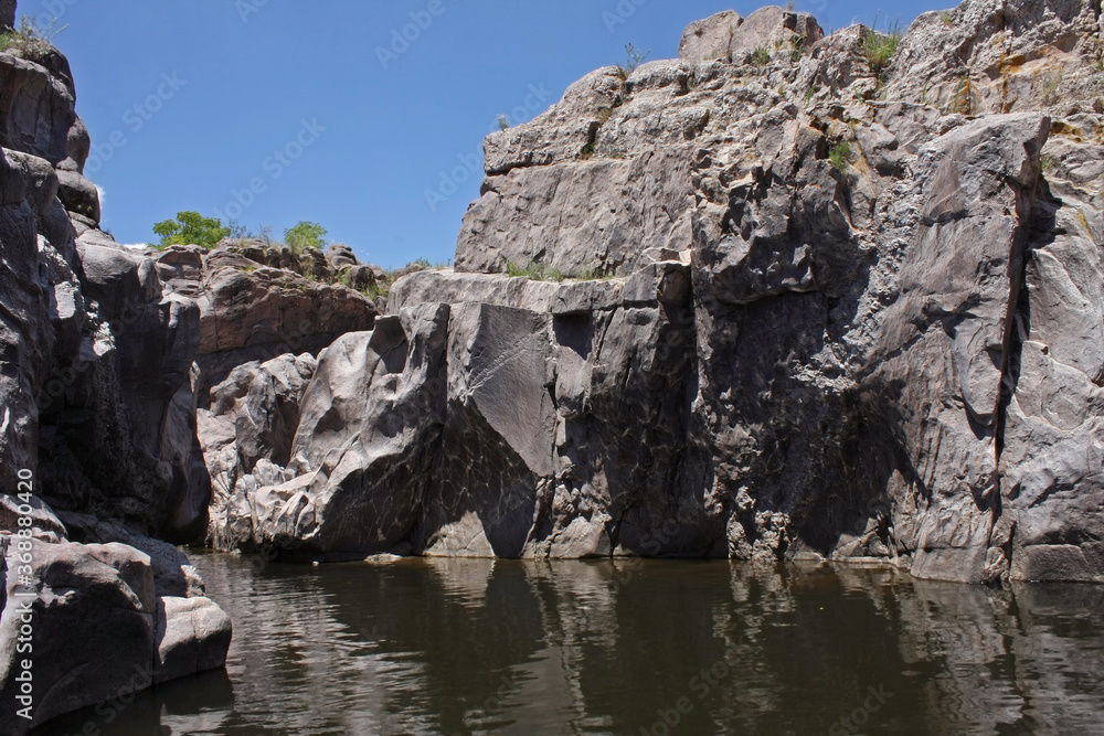 Adventure. Geology. View of the river flowing along the rocky cliffs and stone wall in Mina Clavero, Cordoba, Argentina. Adventure. Geology. View of the river flowing along the rocky cliffs and stone wall in Mina Clavero, Cordoba, Argentina.