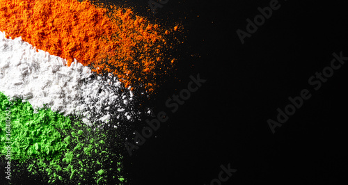 Indian Independence Day celebration background concept. Symbolic flag colors, red, green and orange powders colour splashed over dark background. photo