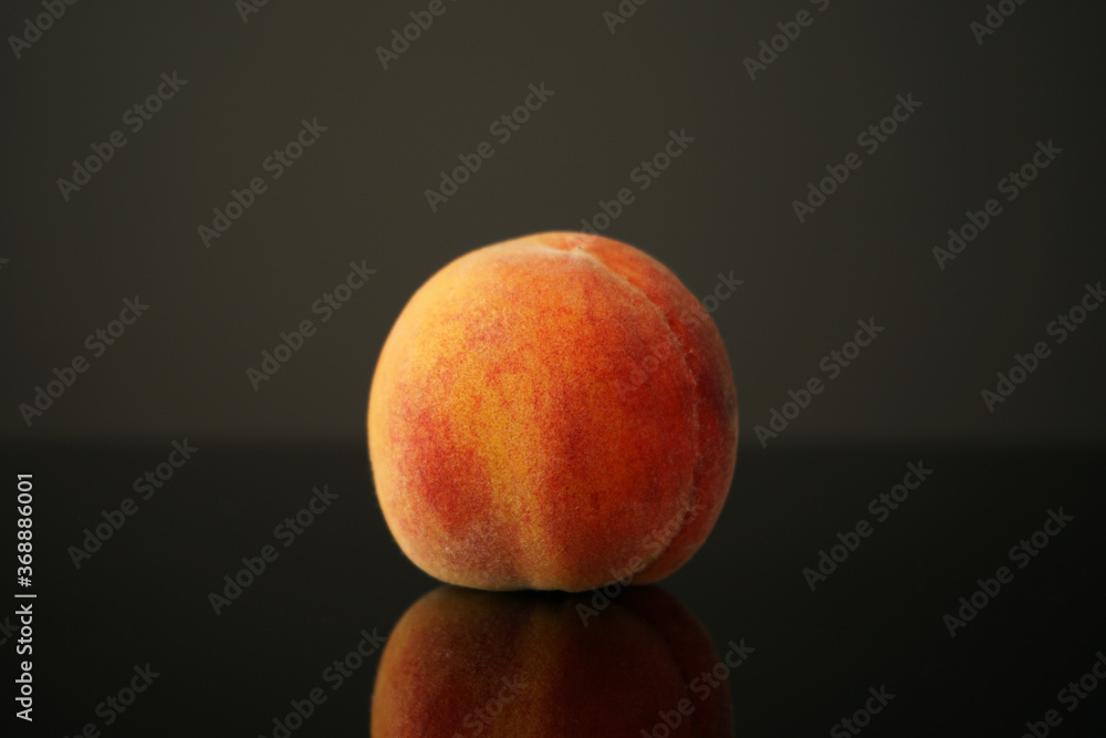 peach lies on the table against a dark background. Beautiful, juicy, ripe and beautiful is reflected in the black glass of the table. Perfect for backgrounds or wallpapers. peach lies on the table against a dark background. Beautiful, juicy, ripe and beautiful is reflected in the black glass of the table. Perfect for backgrounds or wallpapers.