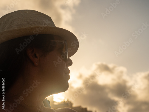 woman in a hat and sunglasses at sunset