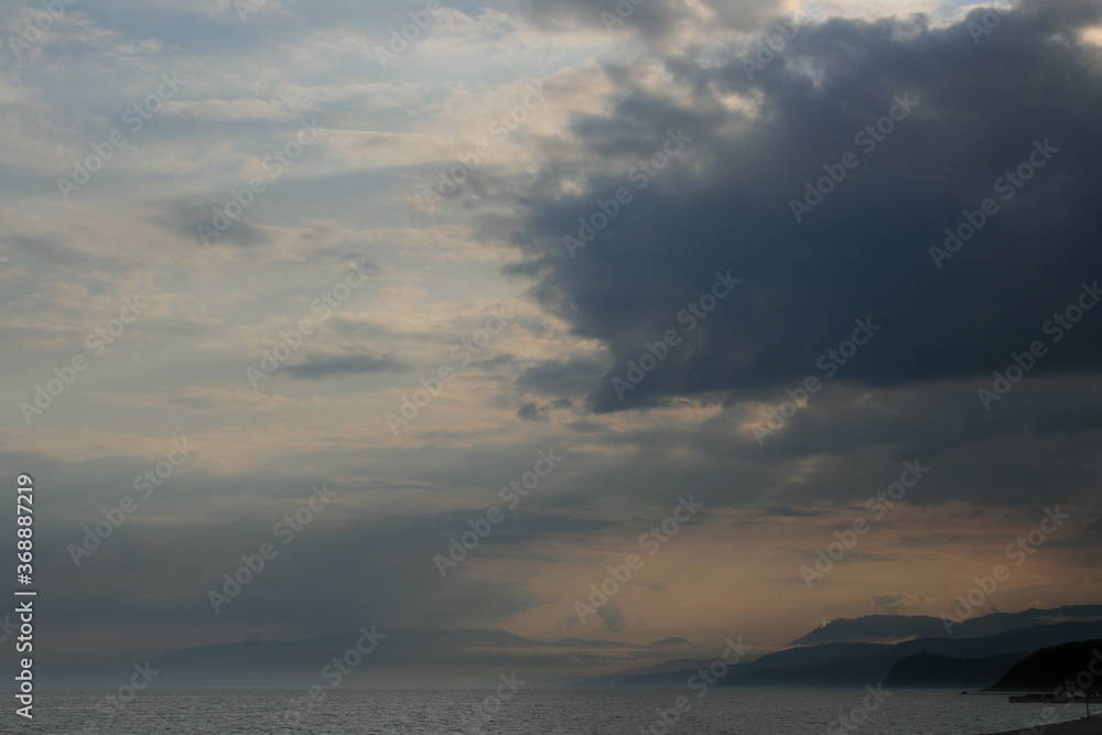 cloudy sunset in the mountains by the sea