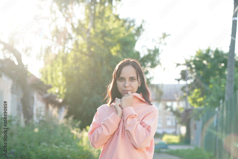 Naklejka premium Portrait of young woman on street during sunset. Close up of pretty female looking at camera and smiling.