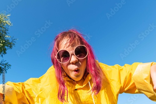 Girl in a yellow raincoat. Summer walk. Blue sky background. © Дарья Колпакова