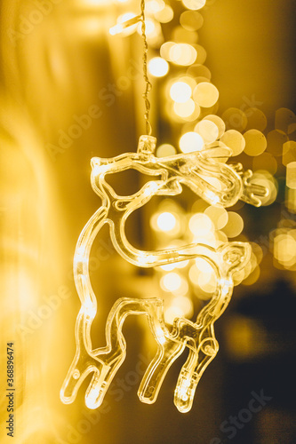 Stylish christmas golden deer illumination  with gold baubles, golden lights bokeh  at home interior. Christmas  decor. Seasons greeting card. Holiday background. Blinking Garlands.   © Natali