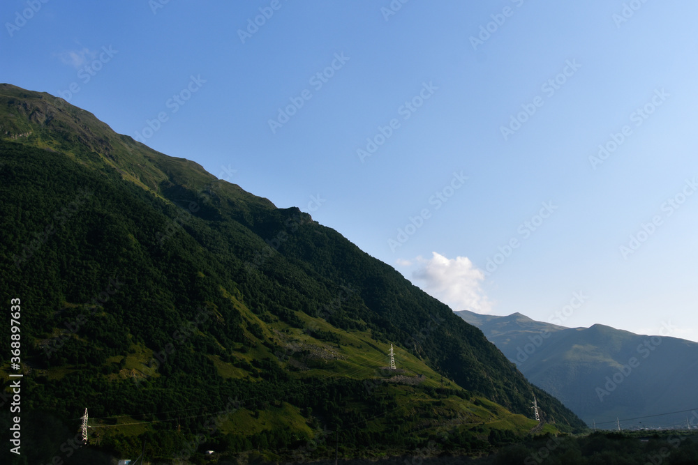 View of the beautiful countryside of North Ossetia. Sunny day. Beautiful summer landscape in the mountains. Grassy fields and hills. Rural landscapes