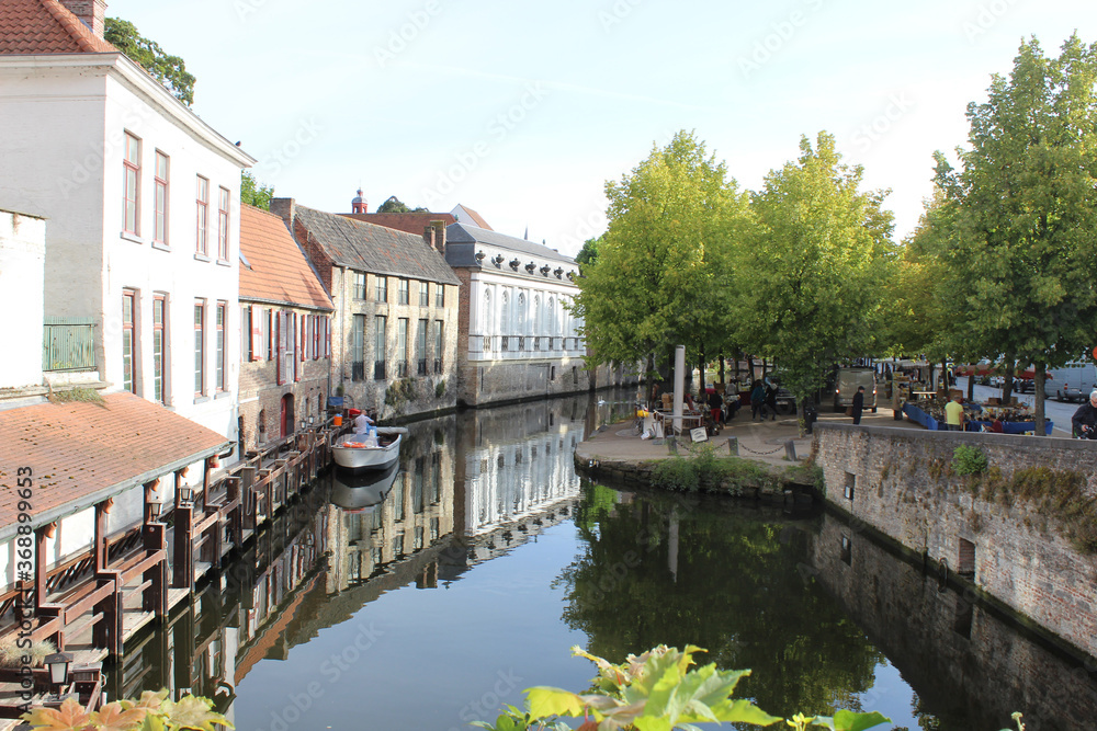 Canal que refleja en sus aguas las casas y los arboles que lo rodean en una mañana de verano