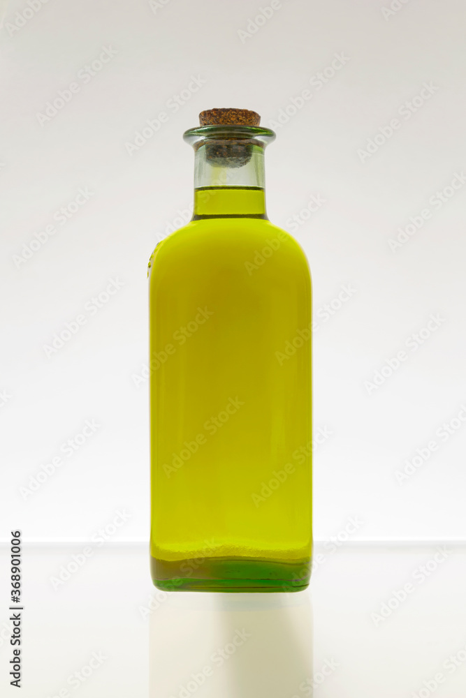 GOLDEN OLIVE OIL GLASS BOTTLE WITH CORK ON WHITE BACKGROUND. FRONT VIEW. GOLDEN OLIVE OIL GLASS BOTTLE WITH CORK ON WHITE BACKGROUND. FRONT VIEW.