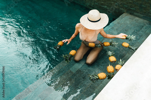 Beauty  Health Concept. Fresh Organic Fruits In Refreshing Pure Water. Beautiful Vegan Woman Relaxing In Swimming Pool With Pineapples. Healthy Lifestyle  Nutrition  Diet. Summer Vacation