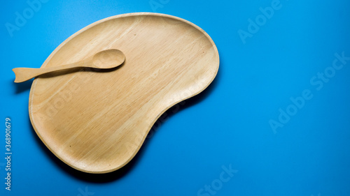 Wooden plates and wooden spoons on blue background