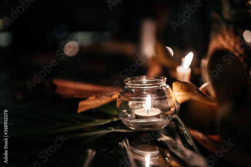 A candle in a glass vase, decoration and various interesting elements on a dark wooden background. Candles burning.