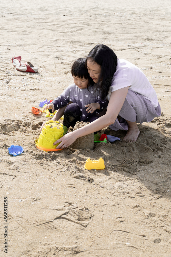 Mother and 3 years old asian kid play sand on the beach. Background for family life and education. holiday with children. Mother and 3 years old asian kid play sand on the beach. Background for family life and education. holiday with children.