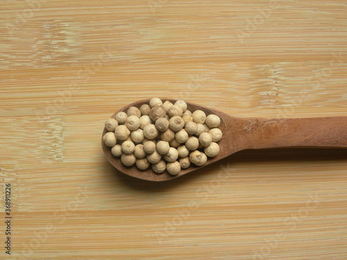 White color raw whole dried pepper on wooden spoon photo