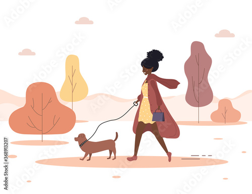 Autumn background. Young african woman walks with dog through the woods. Concept happy girl in brown coat with dachshund or poodle. Vector illustration in flat style.