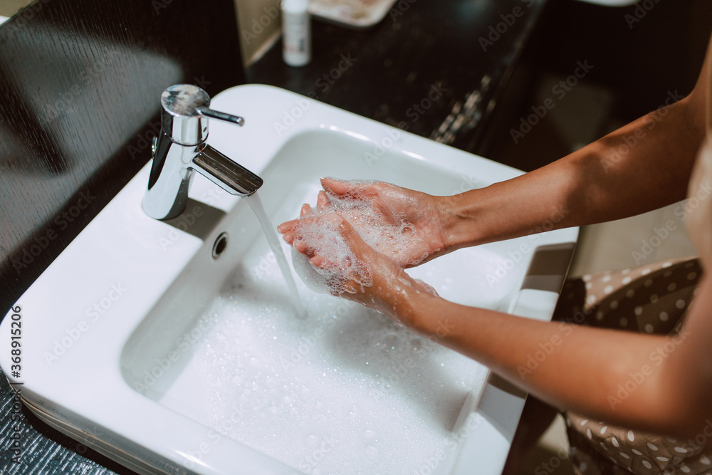 Top view of woman hands while washing hands with soap in the bathroom. Prevention of COVID - 19 coronavirus Top view of woman hands while washing hands with soap in the bathroom. Prevention of COVID - 19 coronavirus