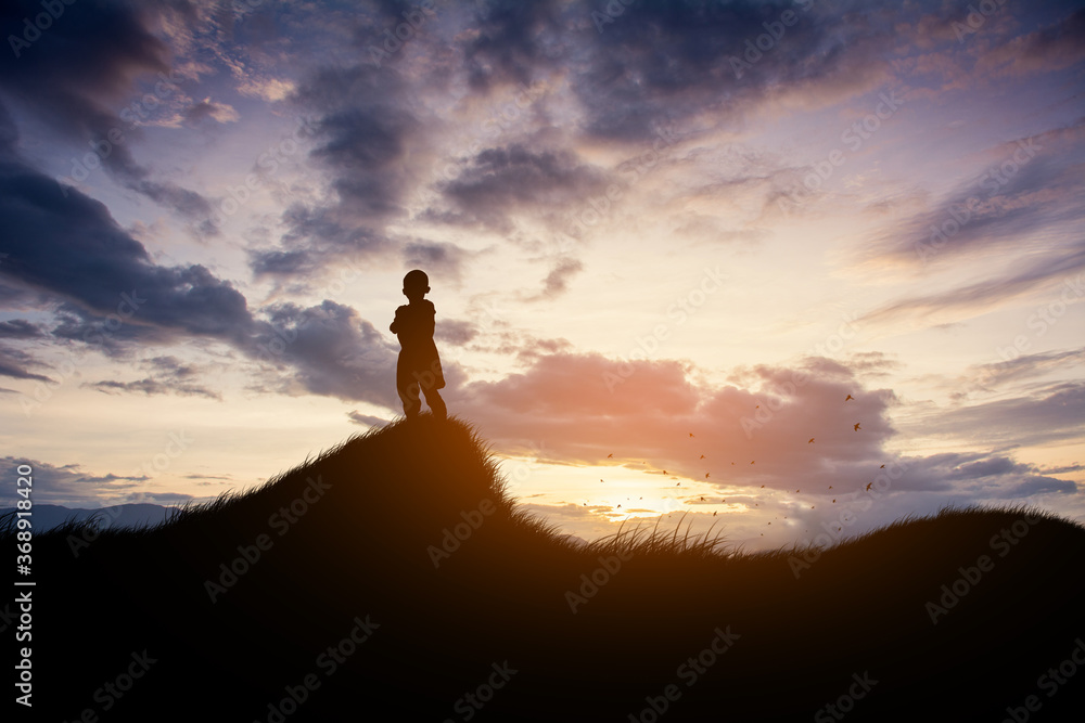 A boy in a helmet looks at the sunset at  the viewpoint.