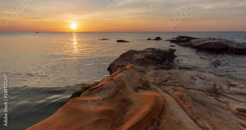 Time lapse: Sunset view on the ocean with reflection and silhouette. A beached foreground log adds interest. Slow motion timelapse 4K footage. Shot at 2160p.