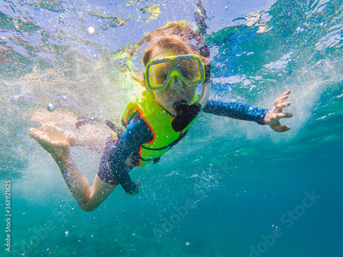 Child wearing snorkeling mask diving underwater