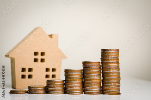 Money coin stack growing graph and house model on gray background.