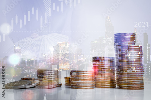 Double exposure of graph and rows of coins on city night background.
